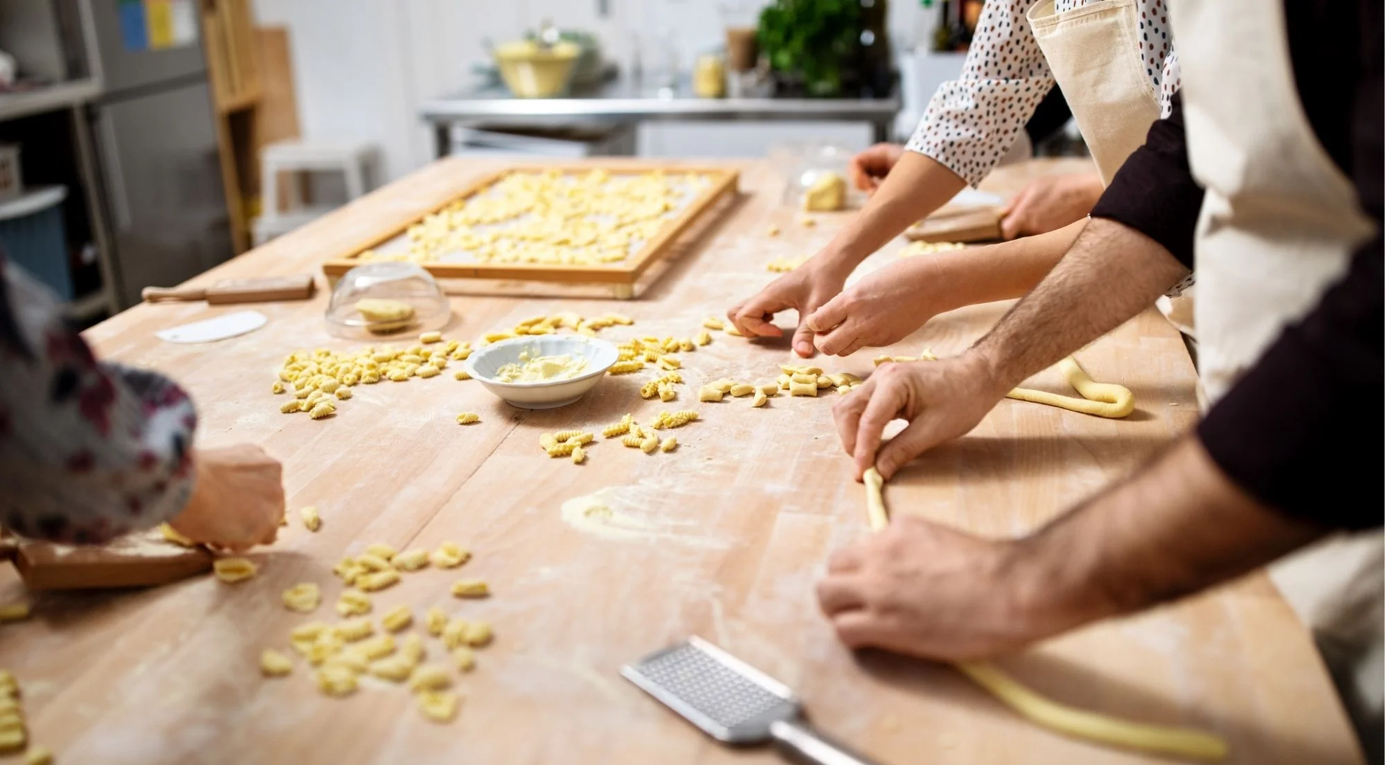 Cooking class participants shaping gnocchi and cavatelli at a wooden work table in Naples